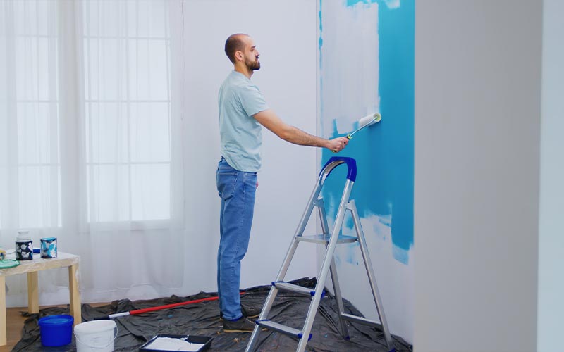 a man painting a room with blue paint adding color to the walls and creating a fresh and vibrant atmosphere
