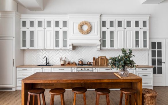 A kitchen with white cabinets and wooden stools.